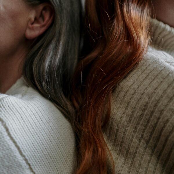 Older woman and younger woman sitting closely together, showing generational connection and shared presence
