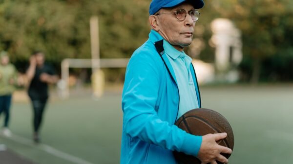 Older man standing on an outdoor basketball court holding a basketball, reflecting focus, experience, and lifelong connection to sport