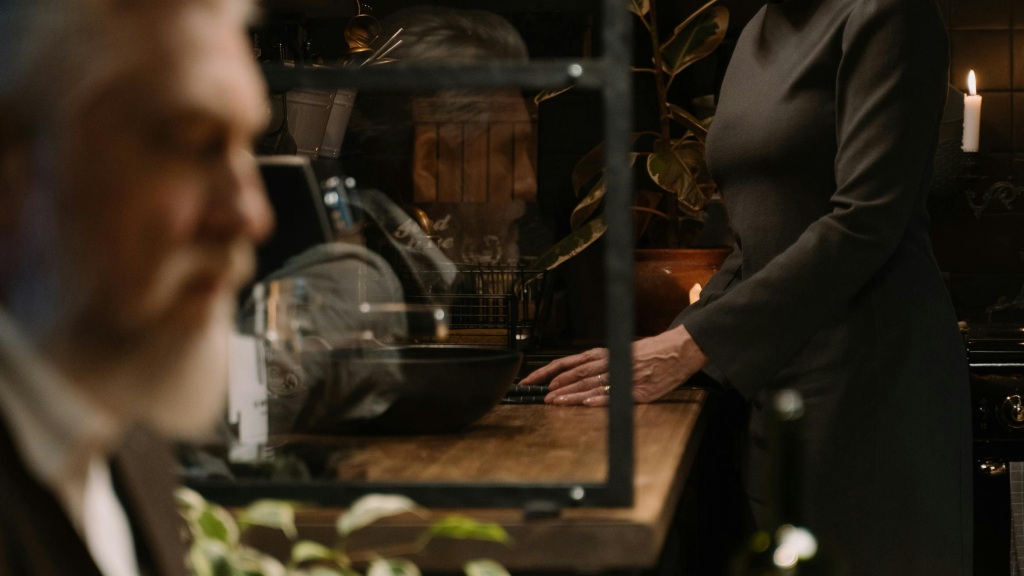 Mature couple sharing a quiet, intimate moment in a dimly lit kitchen, expressing deeper emotional connection later in life