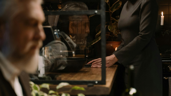 Mature couple sharing a quiet, intimate moment in a dimly lit kitchen, expressing deeper emotional connection later in life