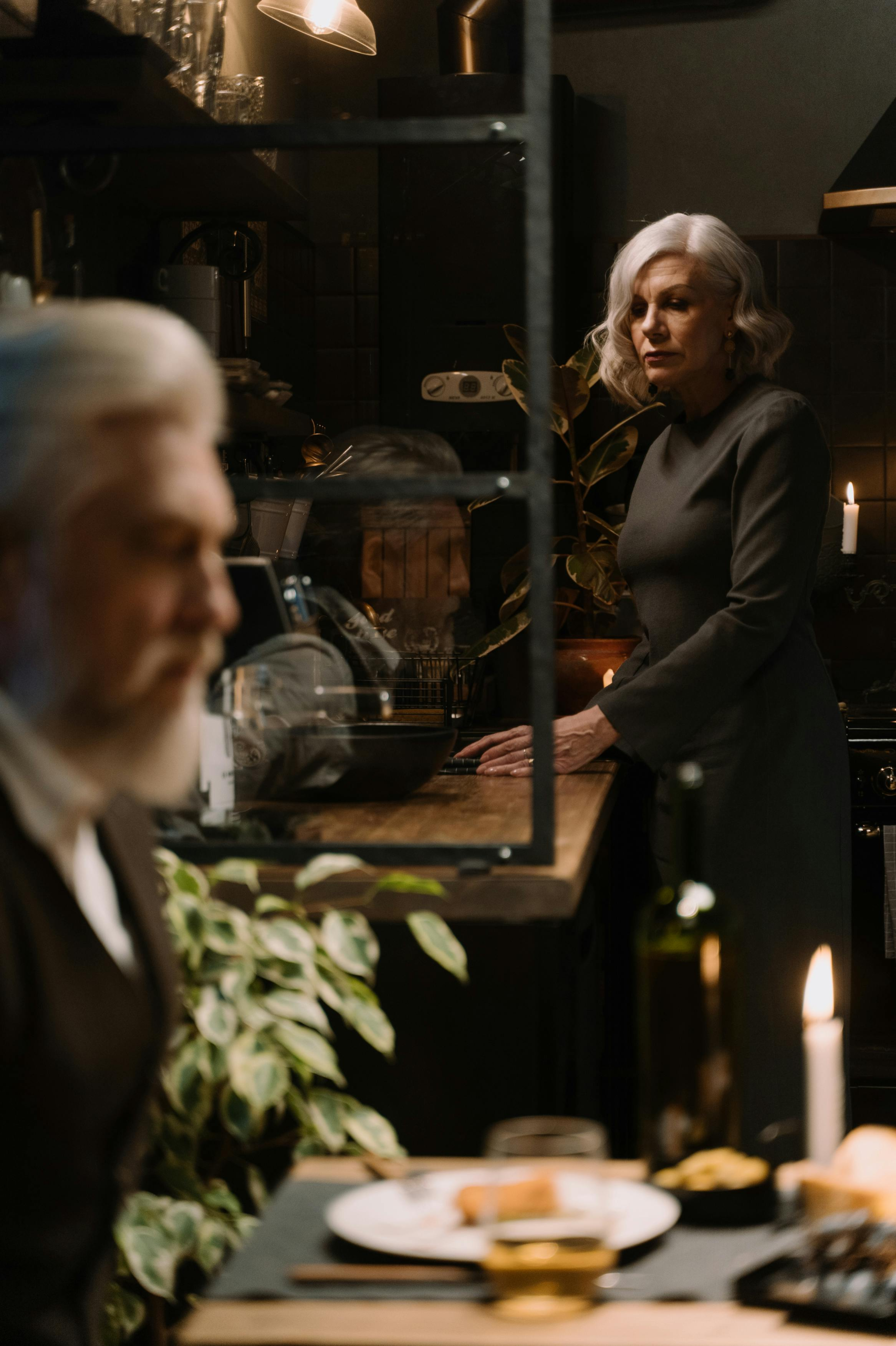 Mature couple sharing a quiet, intimate moment in a dimly lit kitchen, expressing deeper emotional connection later in life