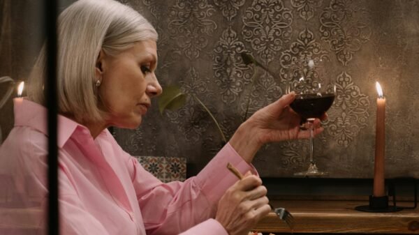 Older woman enjoying a quiet dinner with a glass of wine and candlelight, expressing calm presence and self-care