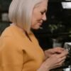 Stylish older woman with silver hair reading a note in a cozy café setting