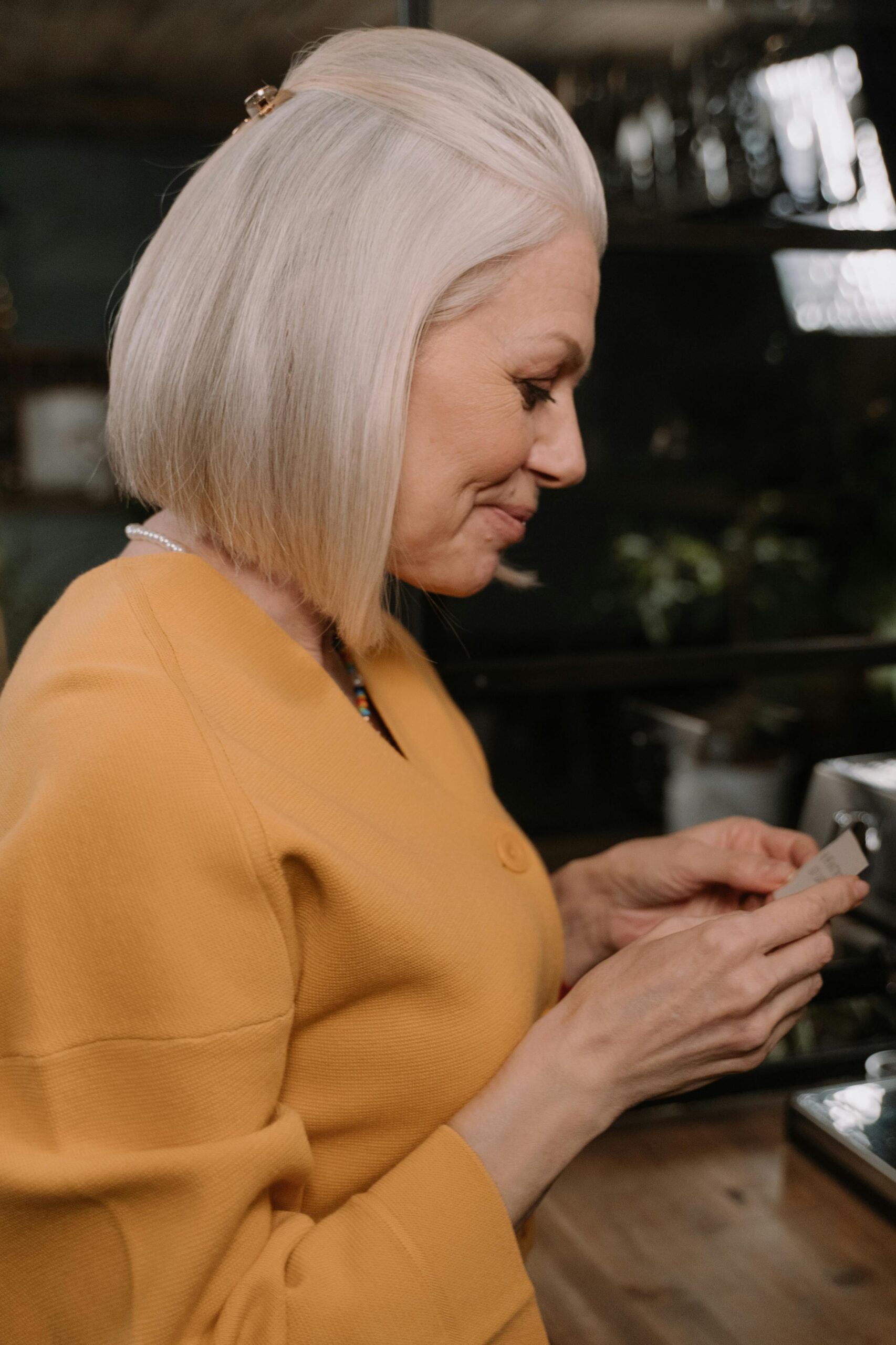 Stylish older woman with silver hair reading a note in a cozy café setting