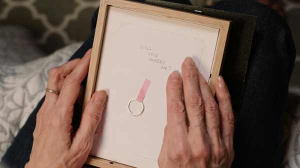 Woman holding a framed note with an engagement ring, symbolizing love and new beginnings