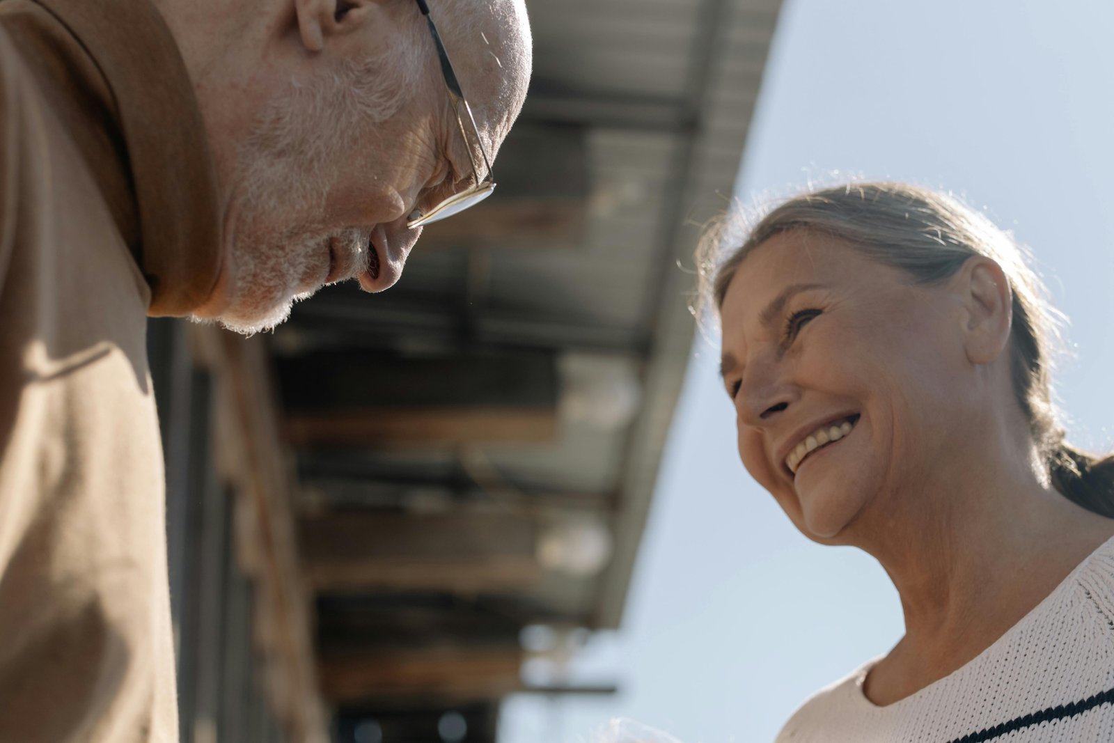 Older couple sharing a quiet laugh outdoors, enjoying connection and presence later in life