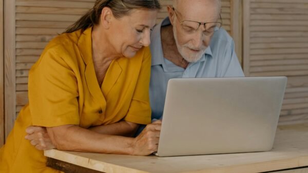 Older couple standing together at a table, looking at a laptop and discussing something thoughtfully at home