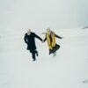 Older couple holding hands while walking across a snowy landscape, symbolizing connection and companionship in midlife
