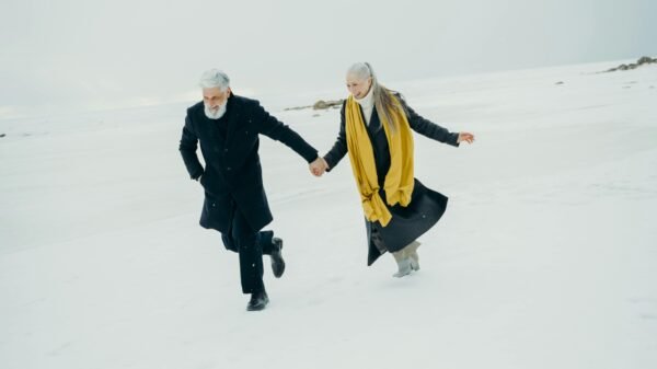 Older couple holding hands while walking across a snowy landscape, symbolizing connection and companionship in midlife