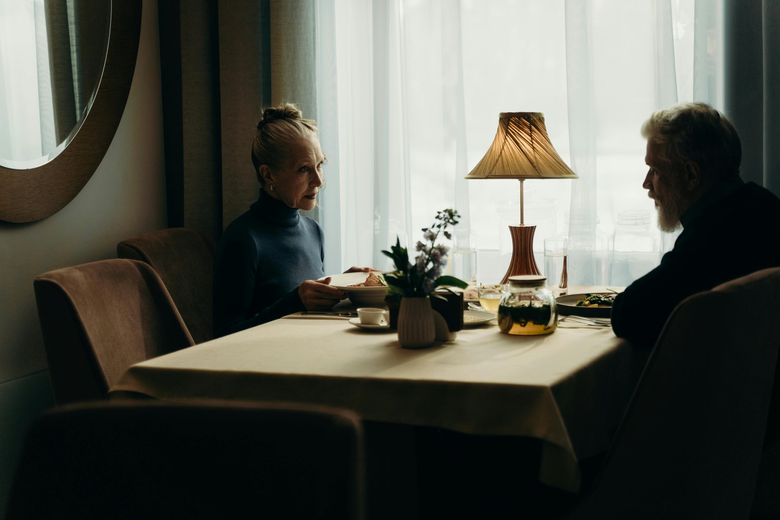 Man and woman in their 50s having an intimate dinner conversation, reflecting emotional closeness and unhurried desire