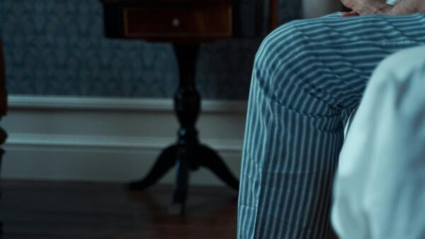 Older man sitting quietly at home, feet in slippers, reflecting in a calm, dimly lit room