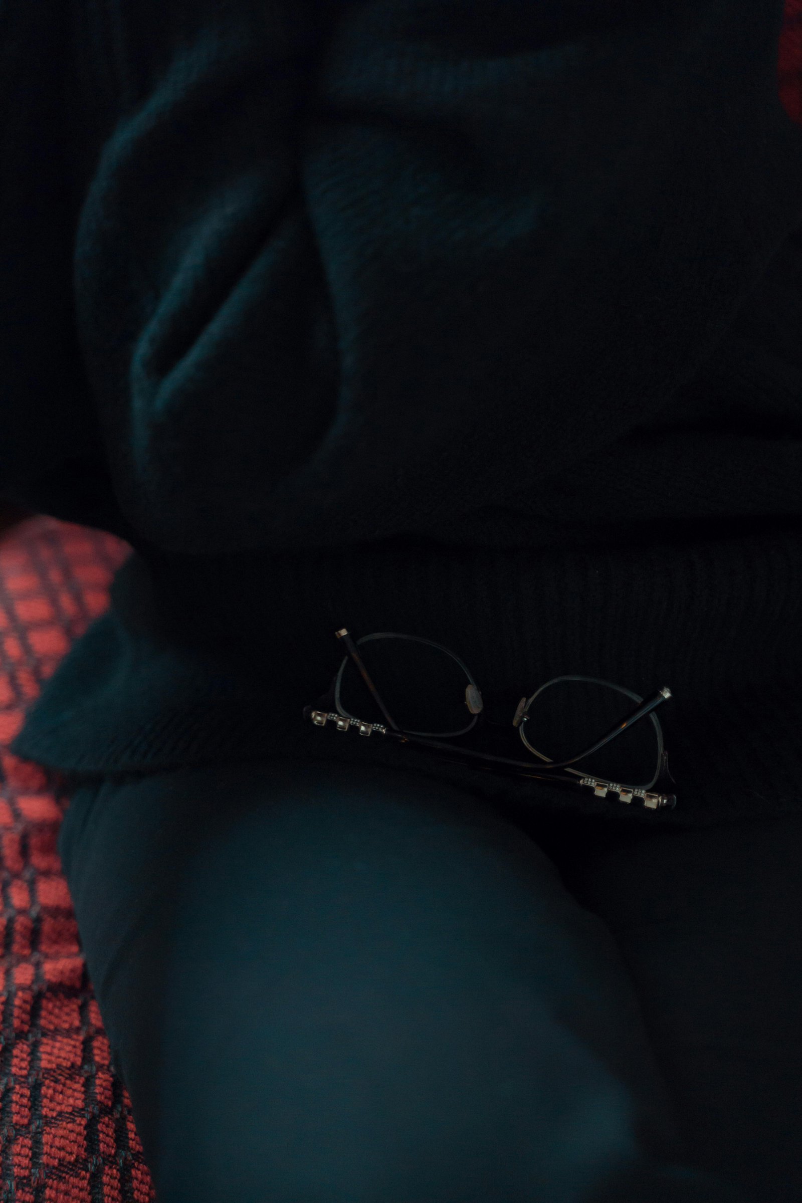 Reading glasses resting on a dark chair, symbolizing quiet reflection and mental rest in midlife