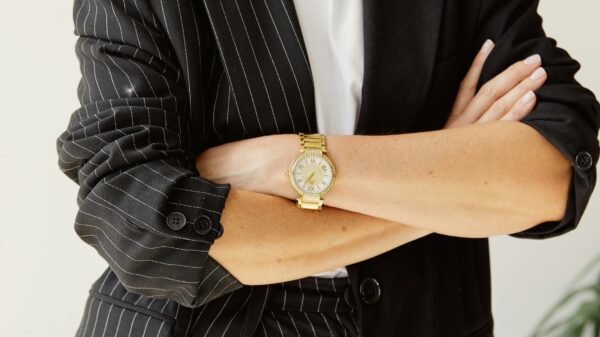 Confident woman in her 40s wearing a black pinstripe suit with arms crossed, expressing quiet authority and self-assurance