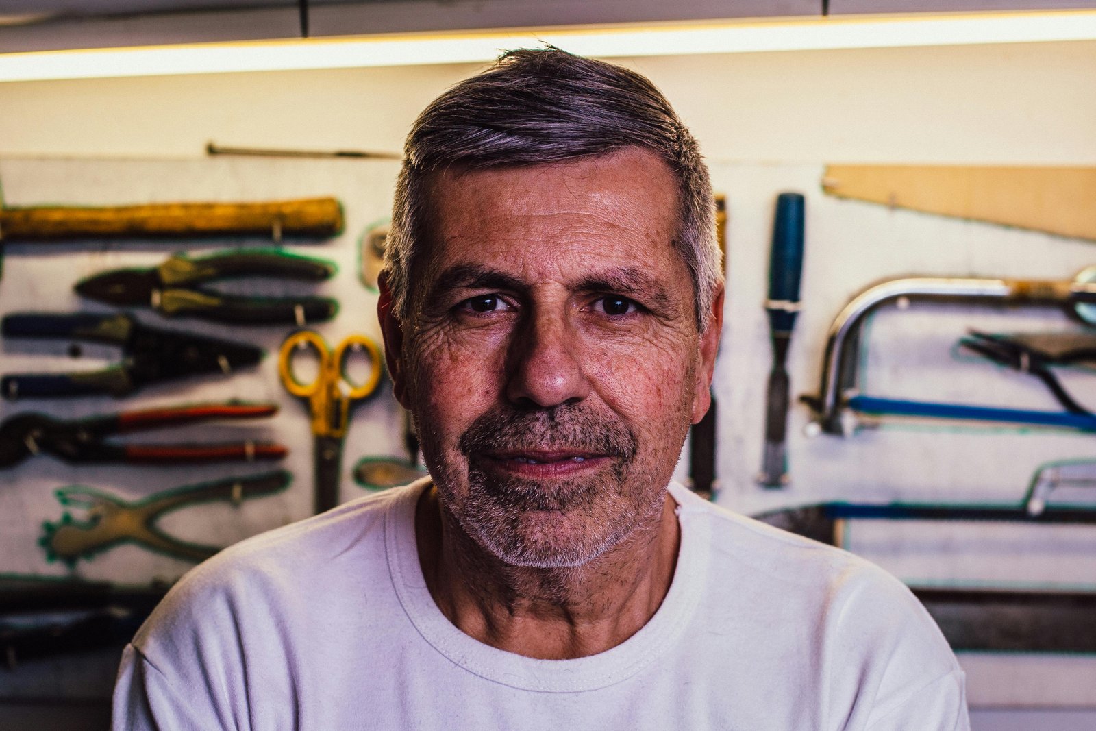 Middle-aged man standing in a workshop surrounded by tools, expressing experience, confidence, and self-assurance gained over time