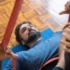 Man in his 40s lying on a mat during a guided stretch session, using resistance bands in a calm indoor space