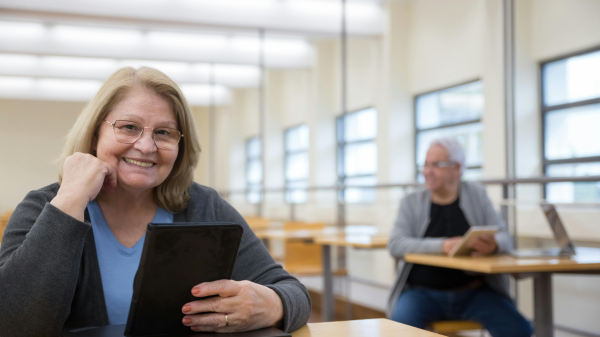 Mature woman holding a tablet and smiling during a technology class for older adults