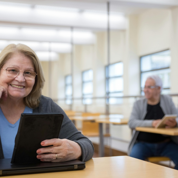 Mature woman holding a tablet and smiling during a technology class for older adults