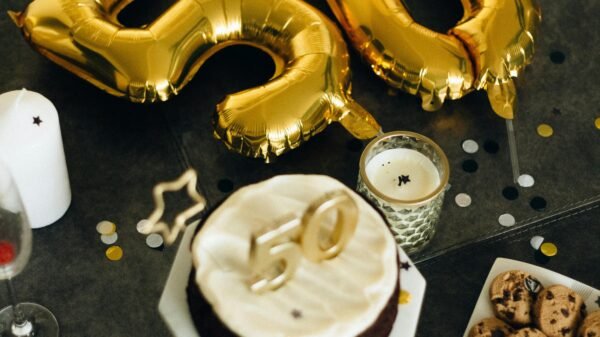 Elegant 50th birthday celebration setup with gold number 50 balloons, cake, desserts, and festive table decor