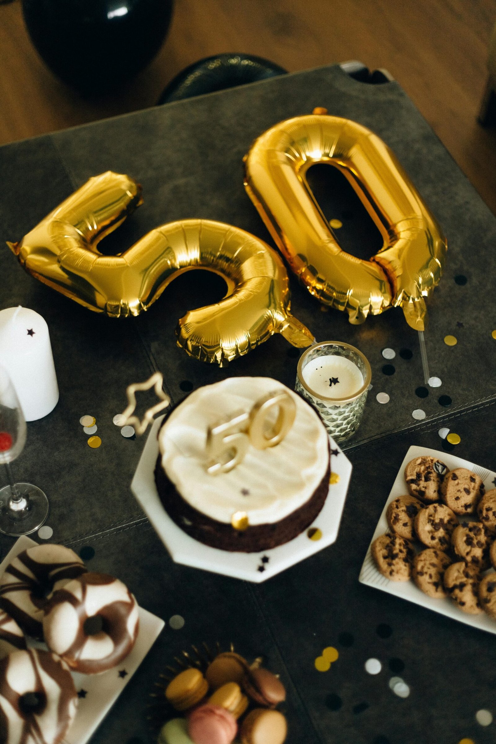 Elegant 50th birthday celebration setup with gold number 50 balloons, cake, desserts, and festive table decor