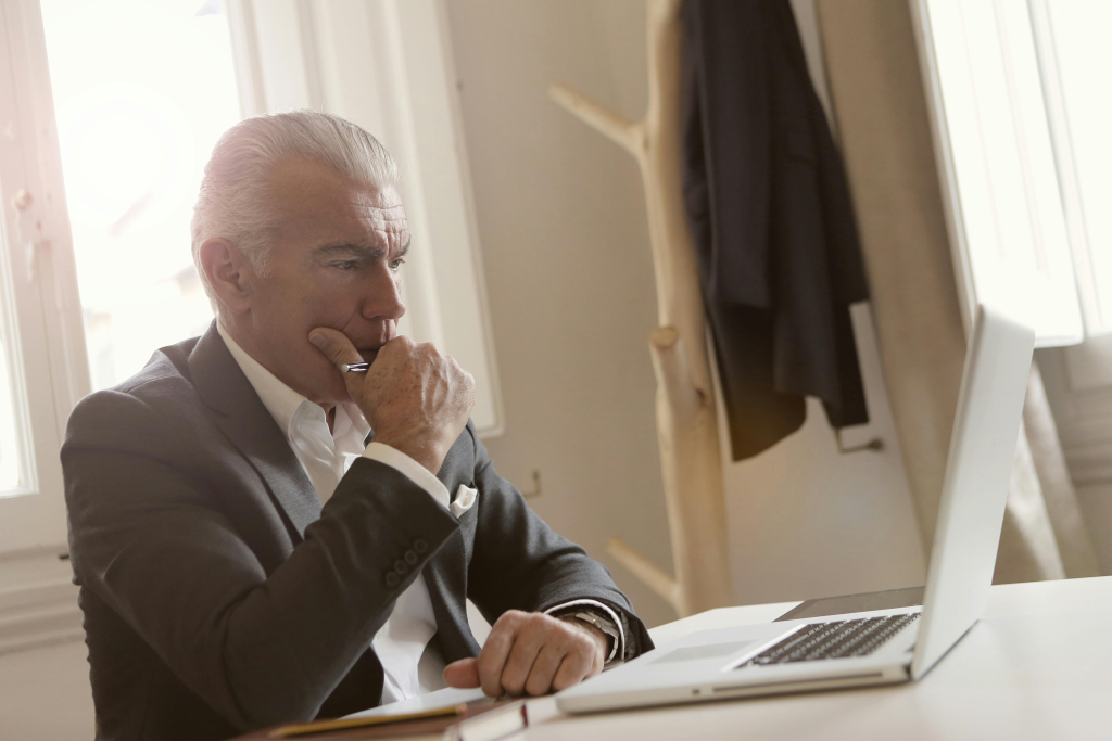 Middle-aged man in a suit concentrating while working on a laptop at a desk