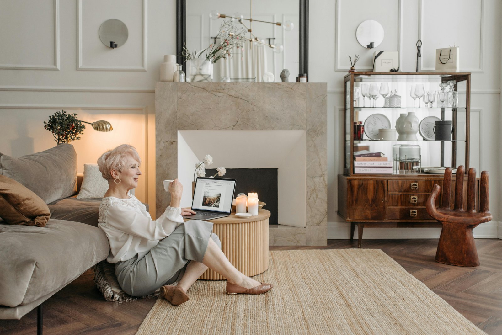 Woman in her 50s relaxing at home with a laptop and coffee, reflecting on a calm and balanced lifestyle