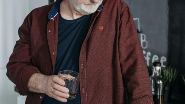 Middle-aged man standing in a kitchen holding a glass, reflecting quietly on life and personal choices