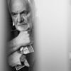 Close-up portrait of an older man holding a framed photo, deep in thought