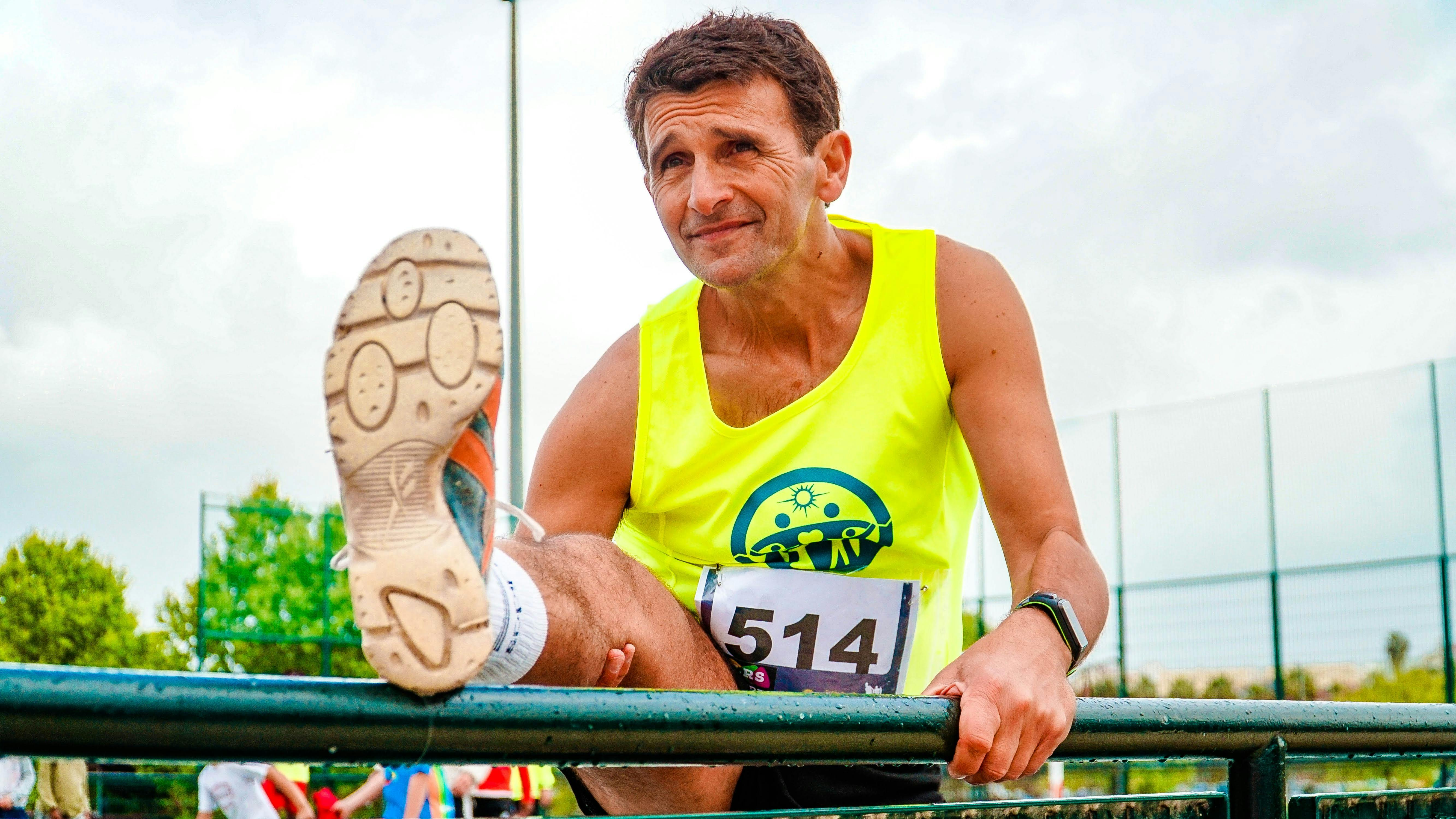 Active middle-aged runner stretching during a race to prevent injury