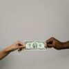 Two people exchanging a two-dollar bill, symbolizing financial decisions, trust, and emotional connections to money