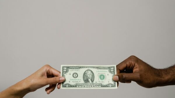 Two people exchanging a two-dollar bill, symbolizing financial decisions, trust, and emotional connections to money