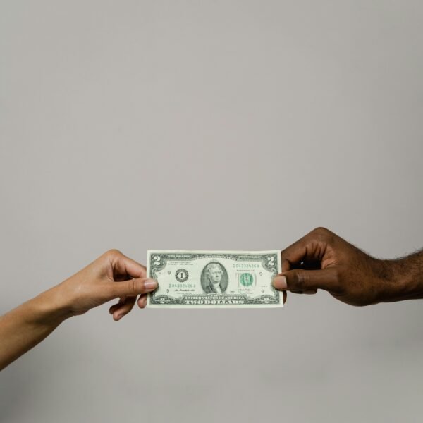 Two people exchanging a two-dollar bill, symbolizing financial decisions, trust, and emotional connections to money
