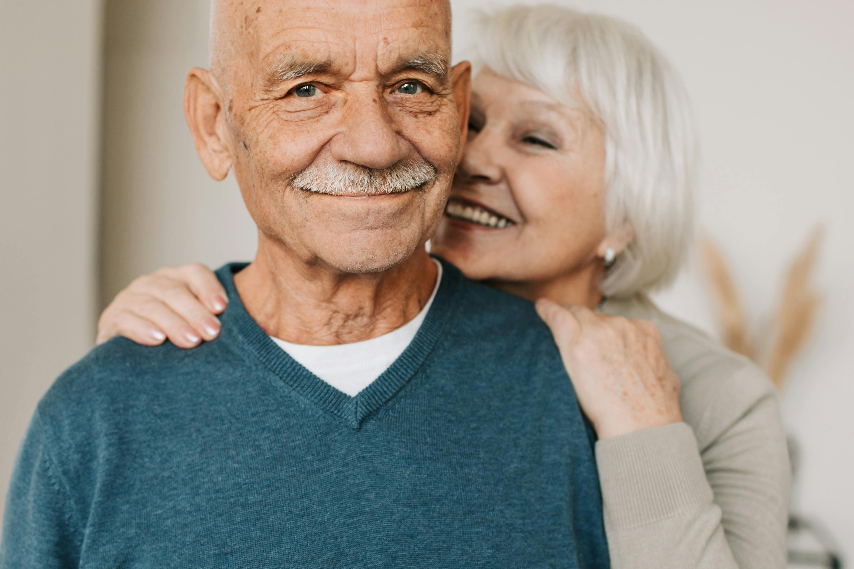 Older couple sharing a gentle embrace indoors, expressing warmth, trust, and emotional intimacy later in life