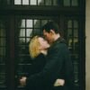 Couple embracing closely in front of a wooden doorway, sharing a quiet, intimate moment with eyes closed