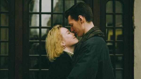 Couple embracing closely in front of a wooden doorway, sharing a quiet, intimate moment with eyes closed