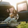 Woman playing guitar at the back of a van at sunset, embracing a creative second act in midlife