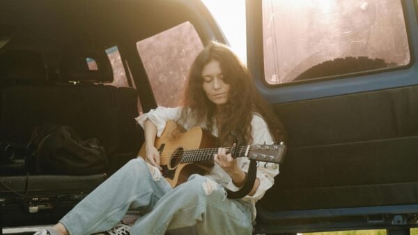 Woman playing guitar at the back of a van at sunset, embracing a creative second act in midlife