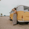 Woman standing beside a vintage van on the beach, pausing during a personal reinvention in midlife