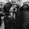 Black and white photo of a couple smiling at each other on a subway train