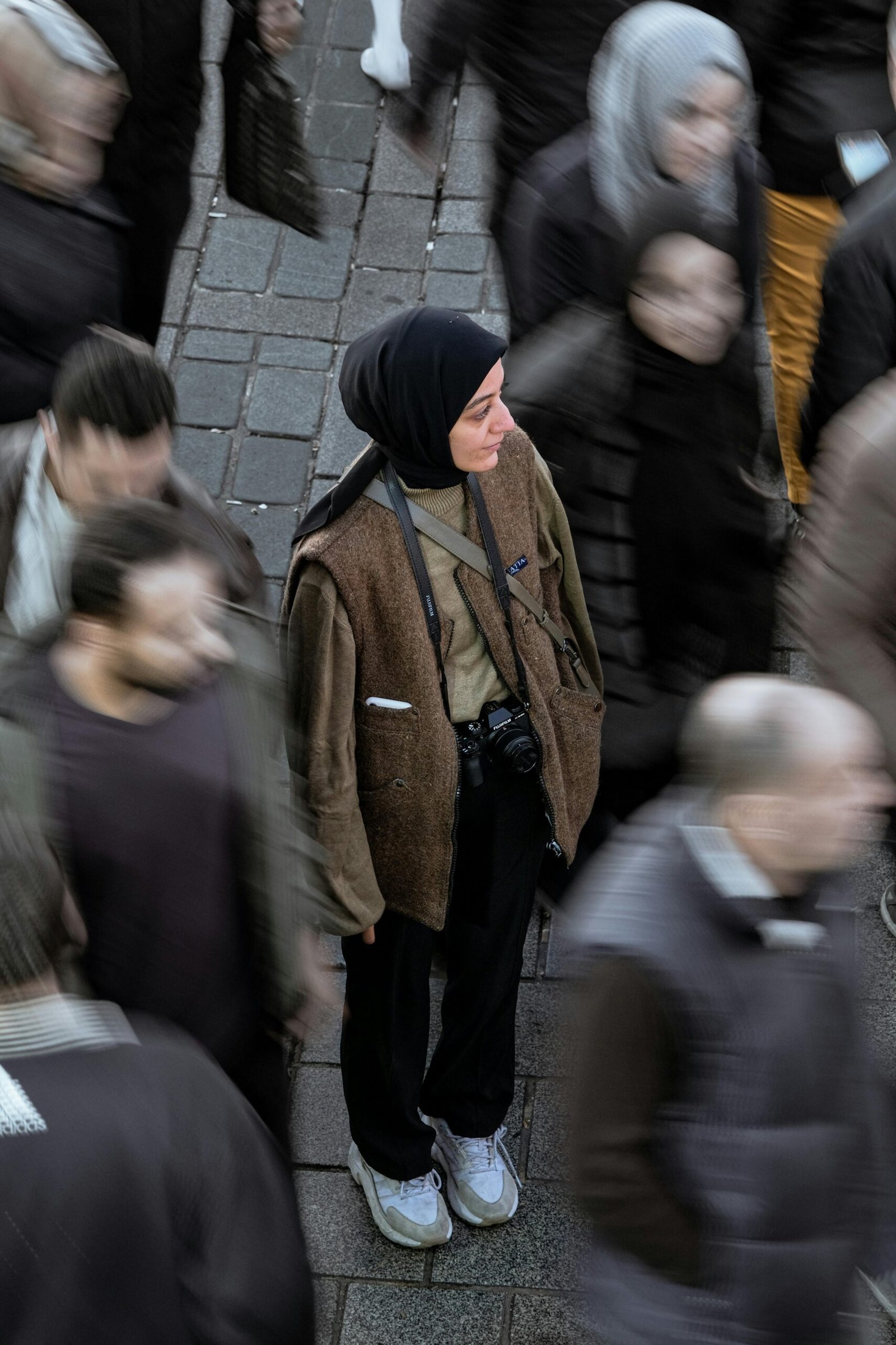 Person standing still while a crowd moves around them, expressing feeling disconnected in everyday life